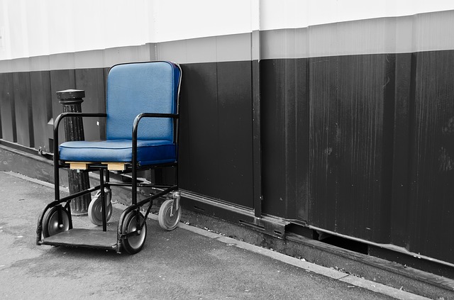 Rollstuhl, älteres, einfaches Modell auf einem Flur an der Wand stehend